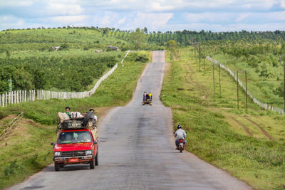 Rear view of people riding motorcycle on road against sky