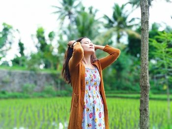 Woman standing by tree on field