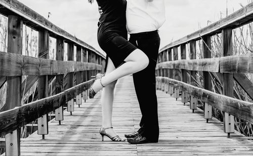 Low section of couple standing on footbridge