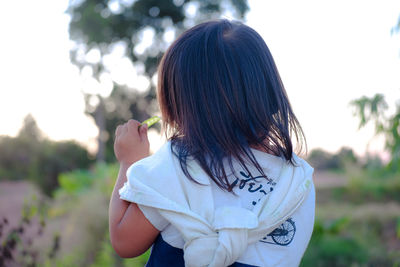 Rear view of girl eating green pea while standing on land