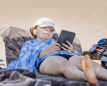 Full length of woman using digital tablet while relaxing on chair