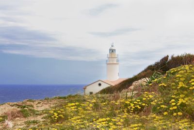 Lighthouse by sea against sky