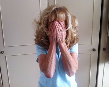 Mature woman hiding face at home