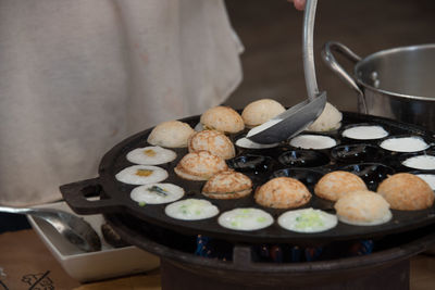 Person preparing food in pan at market stall