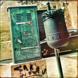 Dust bin by electric box on sidewalk