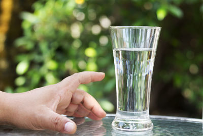 Cropped hand of man reaching for drinking glass on table