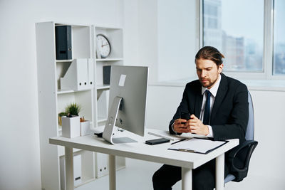 Young man using mobile phone while sitting on table