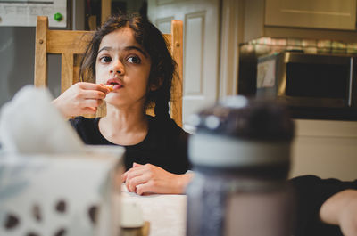Girl looking away while eating food at home