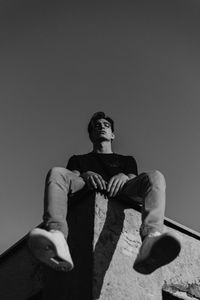 Low angle view of man sitting against sky