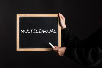 Midsection of man holding blackboard against black background