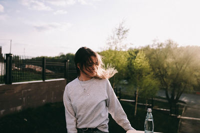 Rear view of woman standing by plants against sky