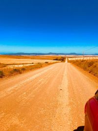 Rear view of man walking on road along countryside landscape