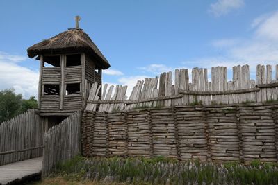 View of wooden wall by building against sky