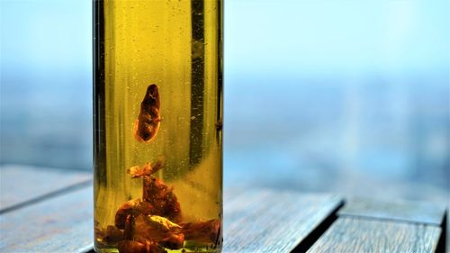 Close up view on bottle of gold olive oil with red paprika at wooden surface