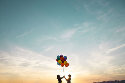 Low angle view of balloons against sky during sunset