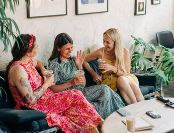 Friends sitting on sofa at home