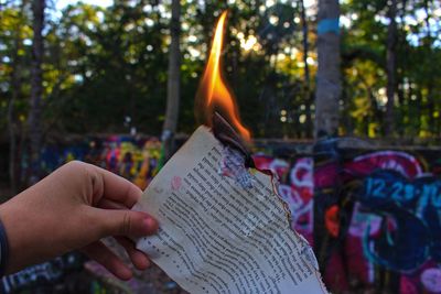 Close-up of hand holding burning paper