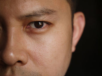 Close-up portrait of man against black background