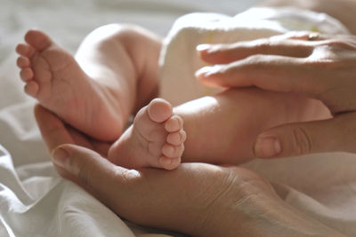 Baby tiny feet in mother hands, on her palm. happy parent touching legs of infant newborn.  close up