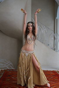 Portrait of beautiful  bellydancer wearing her belly dancing outfit and standing mosaic background
