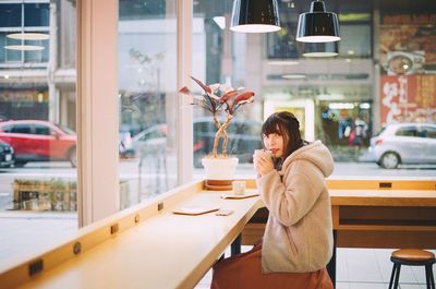 Woman sitting on table in cafe