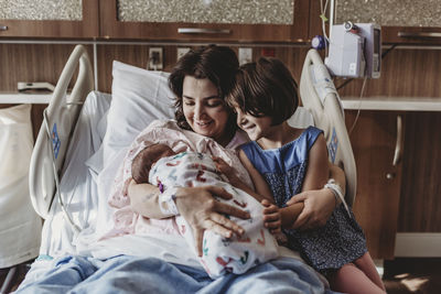 Mid view of mother holding newborn son meeting sister