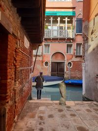 Rear view of man walking in alley amidst buildings