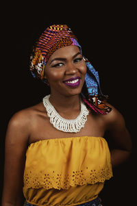 Portrait of fashionable young woman smiling against black background