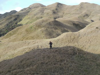 Mid distance view of woman standing on grassy mountain