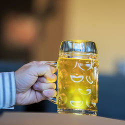 Cropped hand of man holding beer glass on table