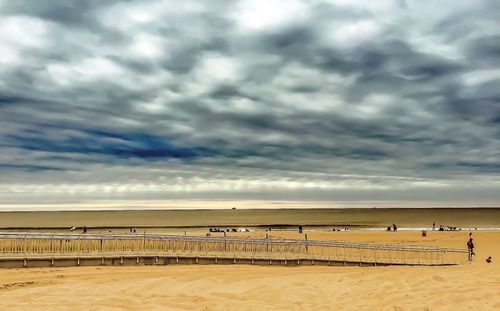 Scenic view of beach against cloudy sky