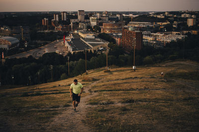 Sportsman jogging on land against city during sunset