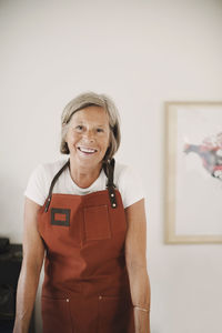 Portrait of happy senior woman wearing apron at home