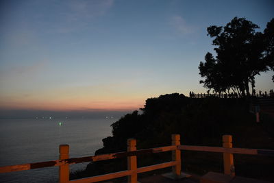 Silhouette trees by sea against sky during sunset