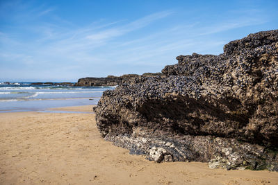 Rock formation on beach against sky