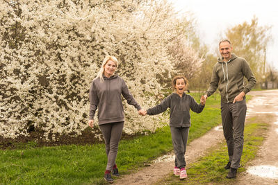 Family having fun with flowering tree in blooming spring garden