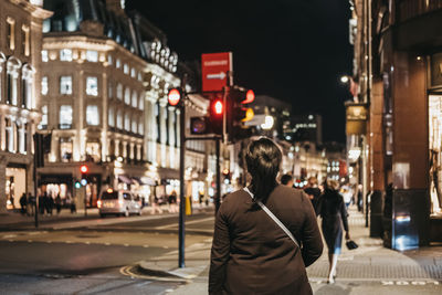 Rear view of man walking on city street at night