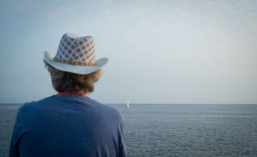 Rear view of man looking at sea against sky