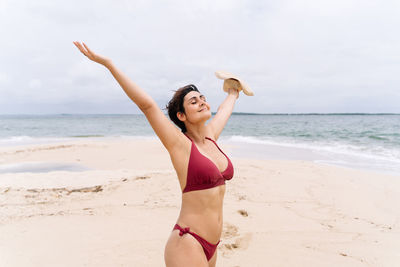 Full length of woman in bikini standing at beach