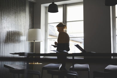 Side view of woman sitting on table at home