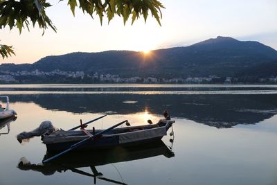 Boats moored in lake against sky during sunset