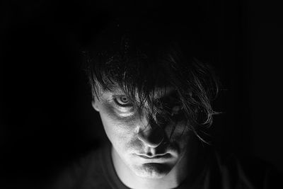 Portrait of young man against black background