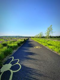 Road amidst field against clear sky