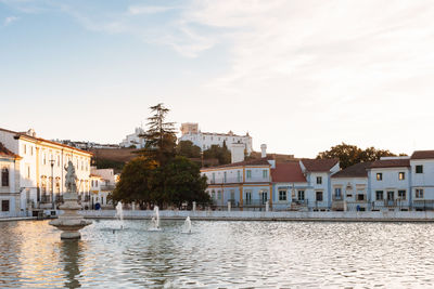 Houses by river in town against sky