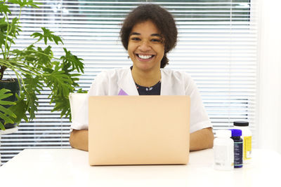 Portrait of young woman using laptop while sitting on table