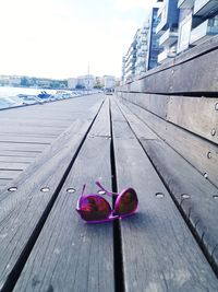 Close-up of pink shoes on footpath in city against sky