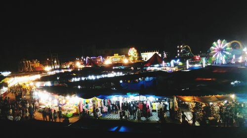 People on illuminated boat against sky at night