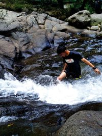 Man standing on rock by river