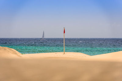 Scenic view of sand and sea against clear sky