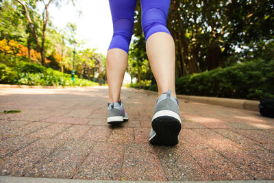 Low section of woman standing on footpath